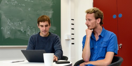 Image of two members of staff meeting in a research office 